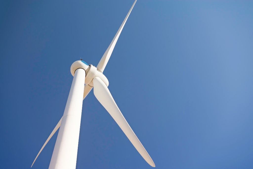 A windmill showing wind power underneath the blue sky.