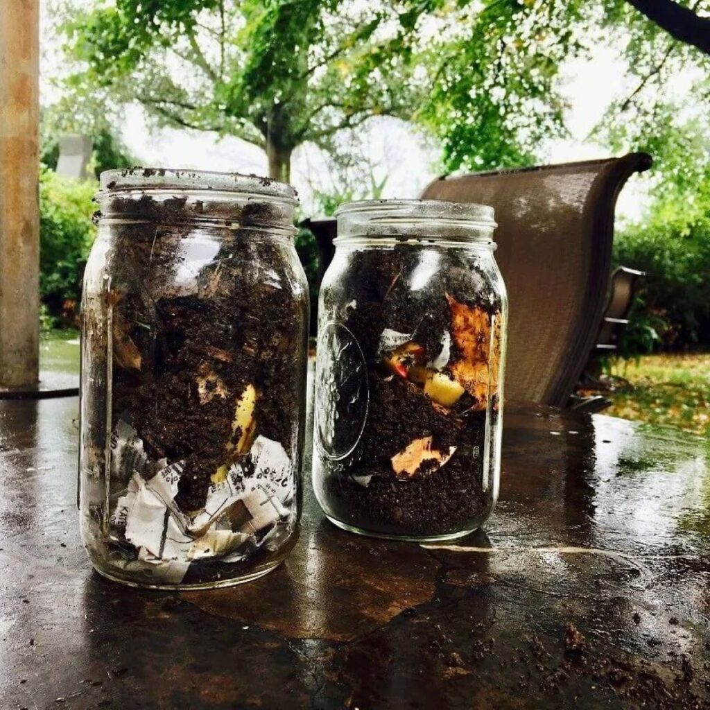 Two jars displaying various composting materials, along with soil.